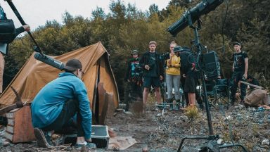 A crew huddled around a tent on an outside shoot