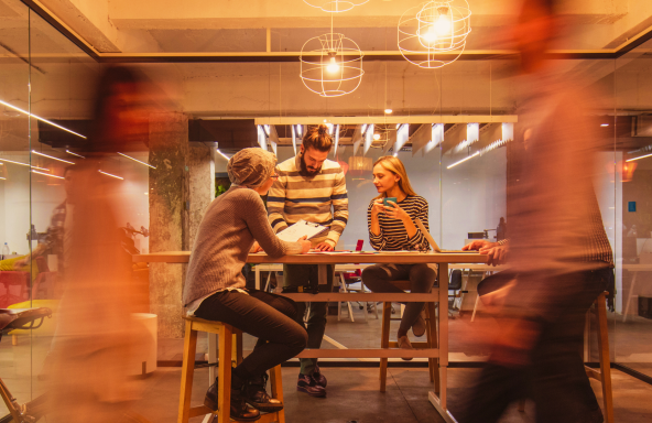 Three busy professionals working in an office meeting room.
