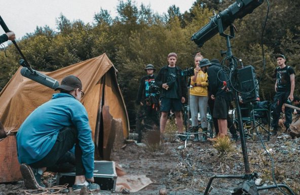 A crew huddled around a tent on an outside shoot