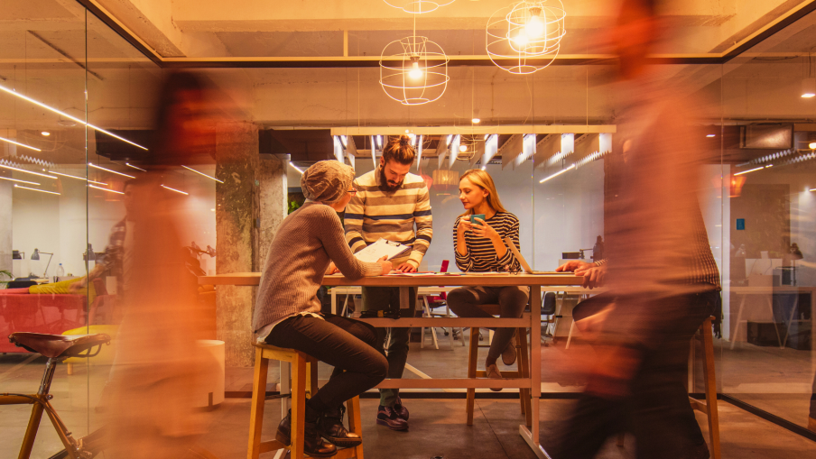 Three busy professionals working in an office meeting room.