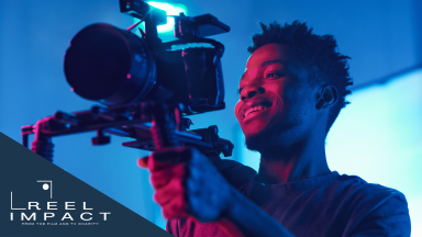 A young Black camera operator on shoot. In the corner of the image is the Film and TV Charity's Reel Impact logo.