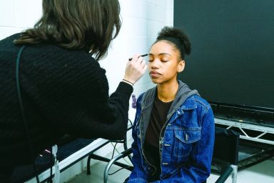 MUA applying make-up to an actor on set.