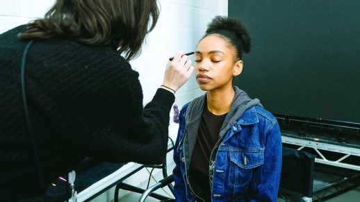 MUA applying make-up to an actor on set.