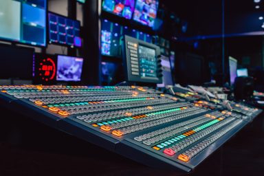 A large vision mixing desk in a studio. The preview screens show camera feeds in a studio.