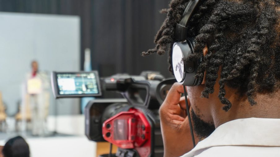 A camera operator is filming a presenter at a conference.