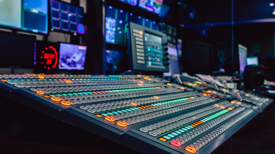 A large vision mixing desk in a studio. The preview screens show camera feeds in a studio.